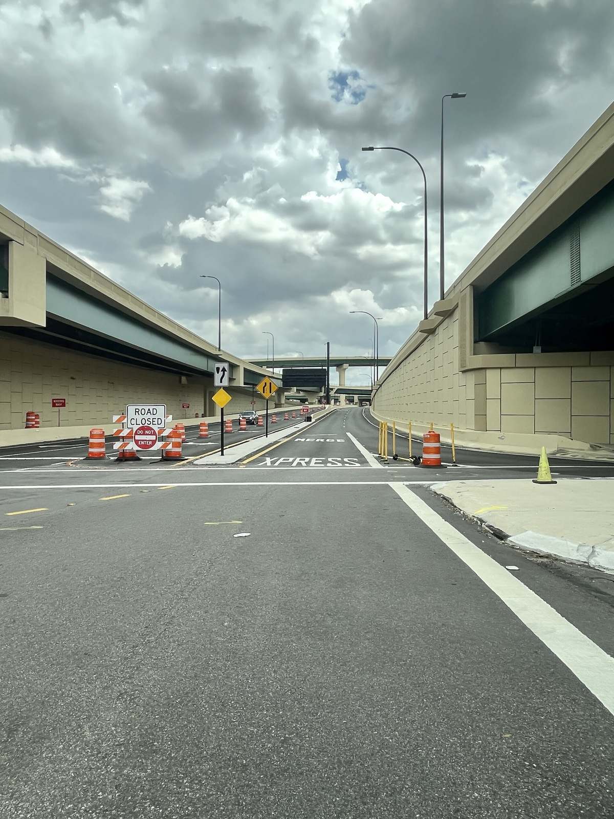 An access ramp to the I-4 Express lanes in Orlando under storm clouds, with orange barrels